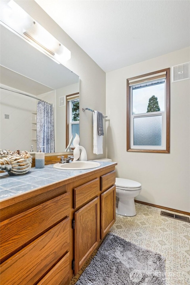 bathroom with vanity, toilet, and visible vents