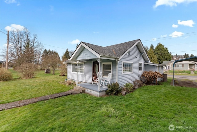 view of front of house with roof with shingles, covered porch, and a front lawn