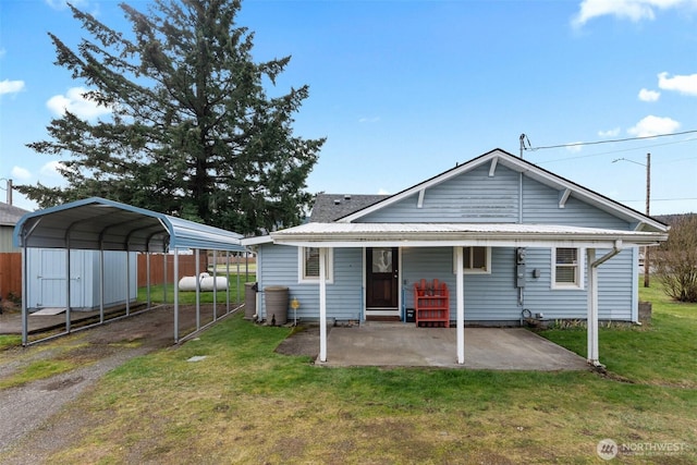 back of house with a detached carport, a yard, and fence