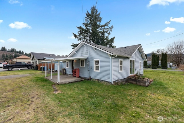 rear view of property with a patio, a yard, and roof with shingles