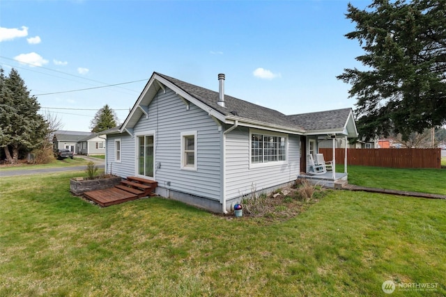 exterior space featuring a lawn, entry steps, roof with shingles, and fence