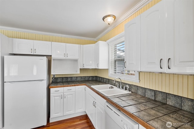 kitchen with a sink, white appliances, white cabinets, tile counters, and dark wood-style flooring