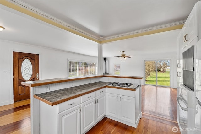 kitchen featuring hardwood / wood-style flooring, white cabinets, tile counters, and oven