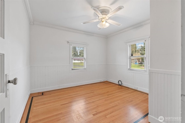 unfurnished room with a wainscoted wall, plenty of natural light, and light wood-style floors