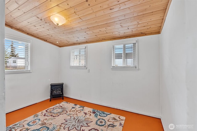 empty room with wooden ceiling, a wood stove, and plenty of natural light