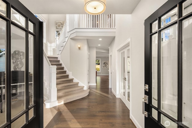 foyer entrance featuring stairway, dark wood-style floors, and baseboards