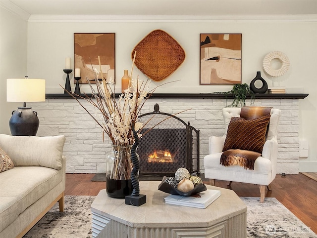 sitting room with wood finished floors, crown molding, and a fireplace