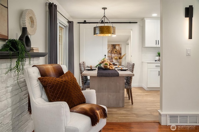 interior space with a barn door, baseboards, visible vents, and light wood finished floors