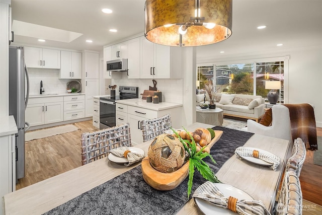 kitchen featuring a sink, stainless steel appliances, light wood-style flooring, and white cabinets