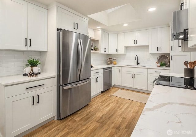 kitchen featuring light wood finished floors, open shelves, a sink, stainless steel appliances, and white cabinetry