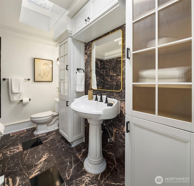 bathroom with marble finish floor and toilet