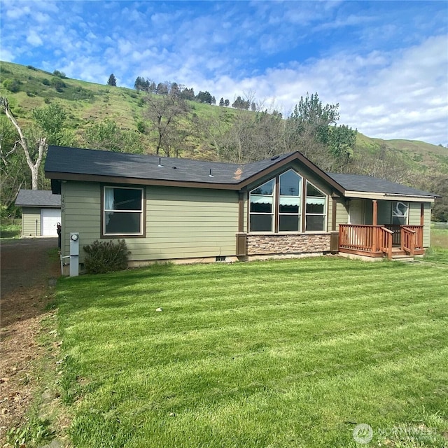 back of property with stone siding and a lawn