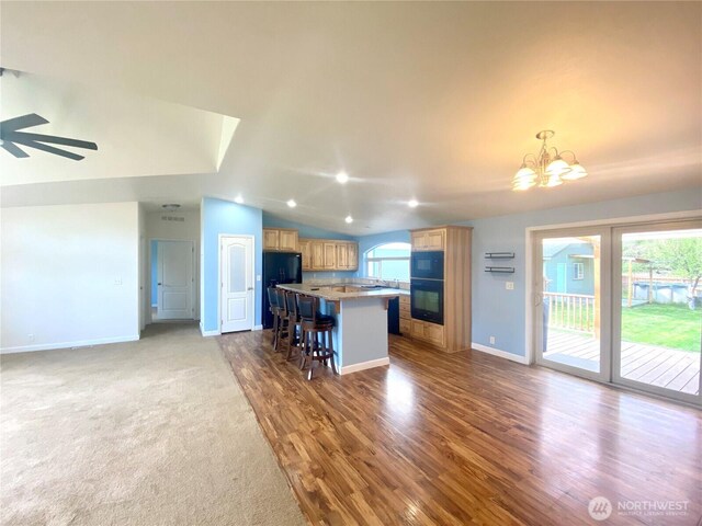 kitchen with a wealth of natural light, a kitchen island, a kitchen bar, and vaulted ceiling