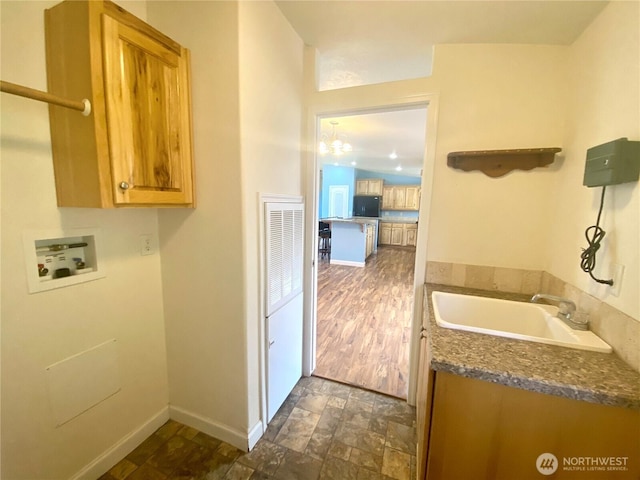 interior space featuring a sink, stone finish flooring, cabinet space, baseboards, and hookup for a washing machine