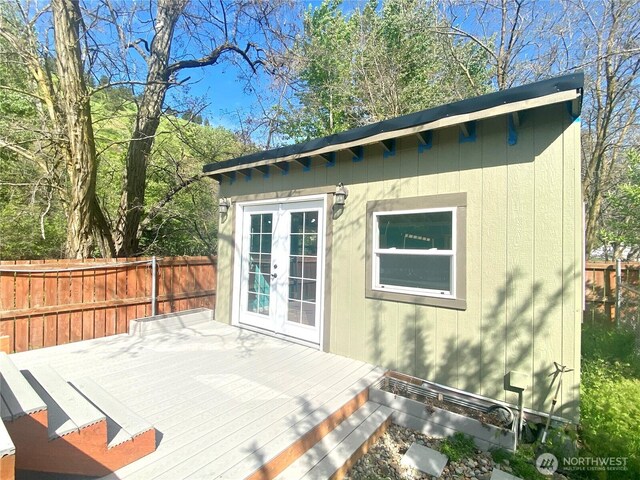 view of outbuilding featuring french doors, an outdoor structure, and fence