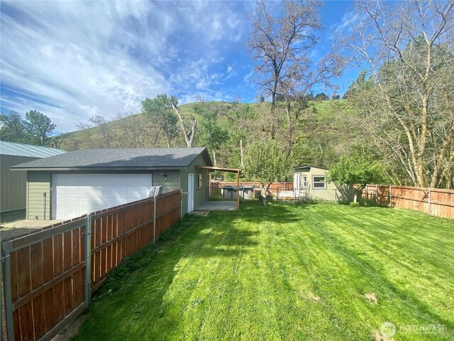 view of yard featuring an outbuilding, a garage, and fence