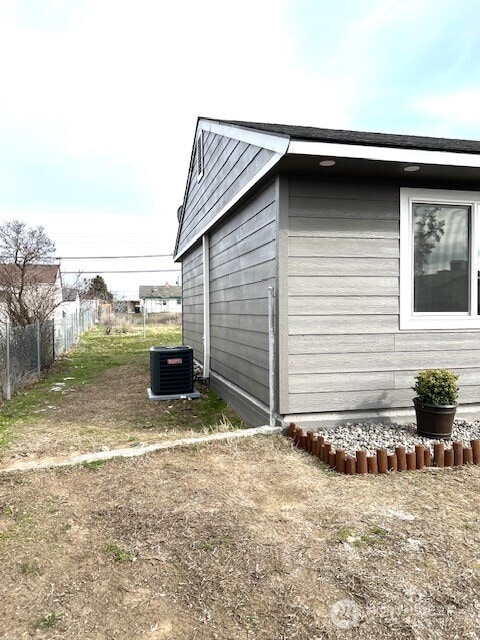 view of outdoor structure featuring central AC unit and fence