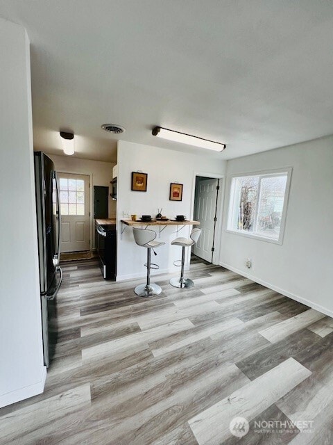 kitchen with a breakfast bar area, light wood finished floors, baseboards, and freestanding refrigerator