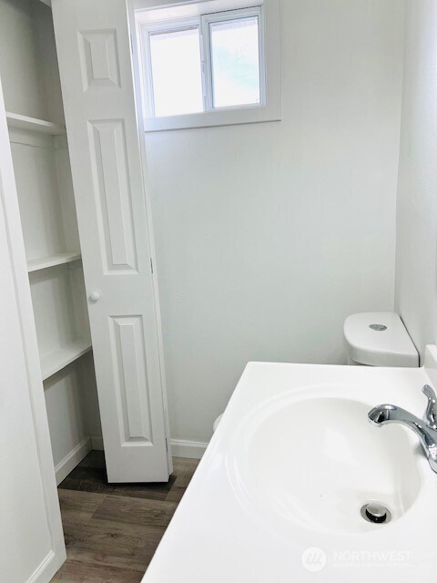 bathroom featuring a sink, baseboards, toilet, and wood finished floors