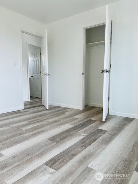 unfurnished bedroom with a closet, baseboards, and wood finished floors