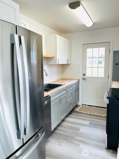 kitchen with a sink, electric panel, freestanding refrigerator, range, and dishwasher