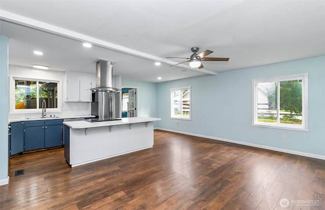 kitchen featuring light countertops, exhaust hood, visible vents, and a sink