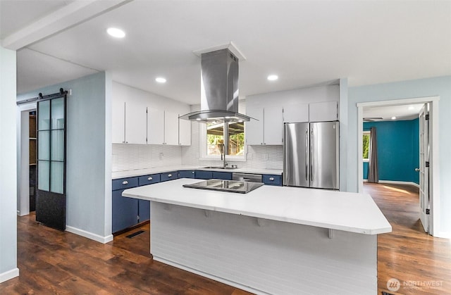 kitchen with backsplash, island exhaust hood, freestanding refrigerator, and a barn door