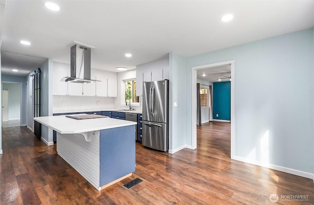 kitchen with a sink, light countertops, island exhaust hood, freestanding refrigerator, and dark wood-style flooring