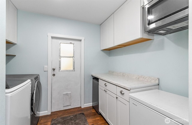 laundry room with cabinet space, independent washer and dryer, dark wood-style flooring, and baseboards