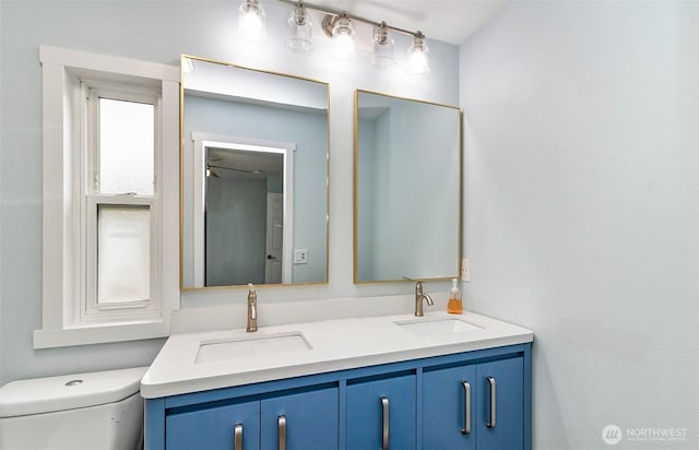 bathroom featuring double vanity, toilet, and a sink