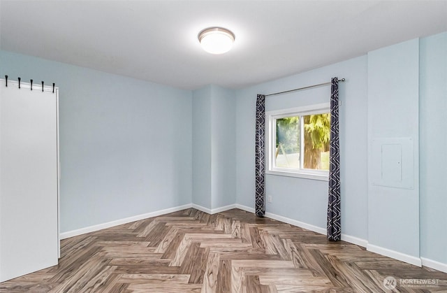 empty room featuring electric panel and baseboards