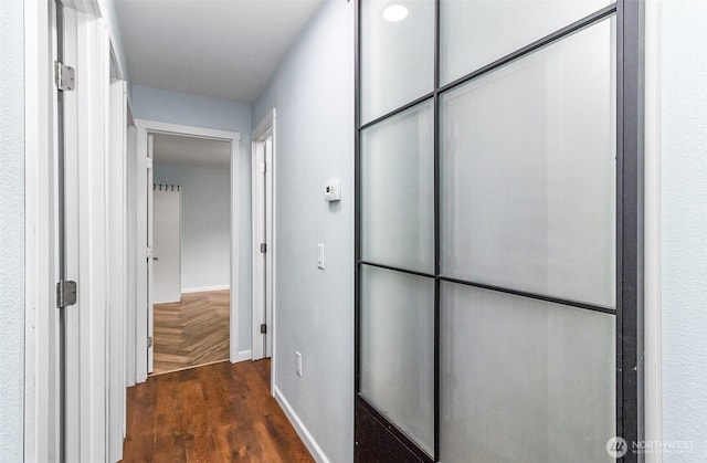 corridor featuring parquet flooring and baseboards