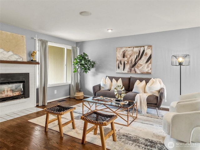 living room featuring wood finished floors, a fireplace, visible vents, and baseboards