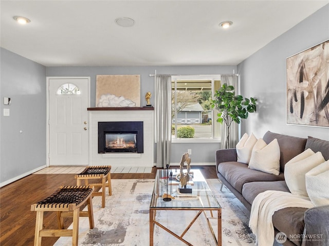 living room featuring a glass covered fireplace, baseboards, and wood finished floors