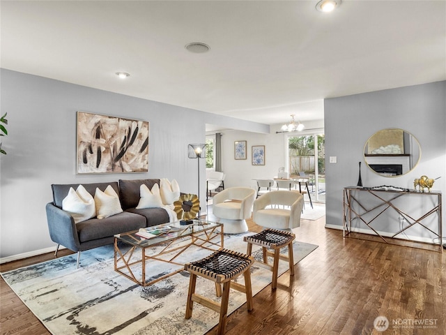 living area with baseboards, an inviting chandelier, and wood finished floors