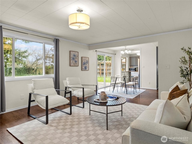 living area with a notable chandelier, baseboards, and wood finished floors