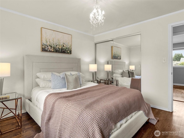 bedroom featuring wood finished floors, baseboards, a closet, crown molding, and a chandelier