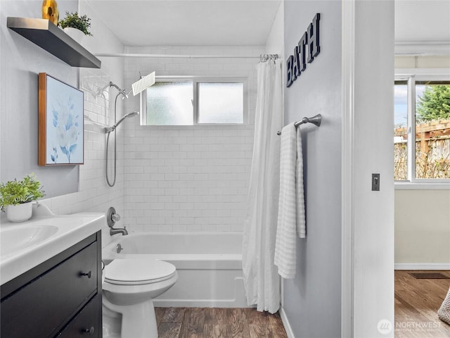 full bathroom with a wealth of natural light, vanity, shower / bath combo, and wood finished floors