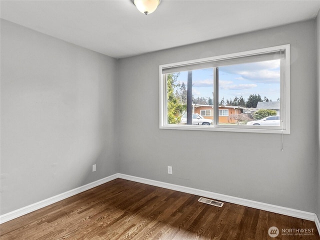 unfurnished room featuring visible vents, baseboards, and dark wood-type flooring