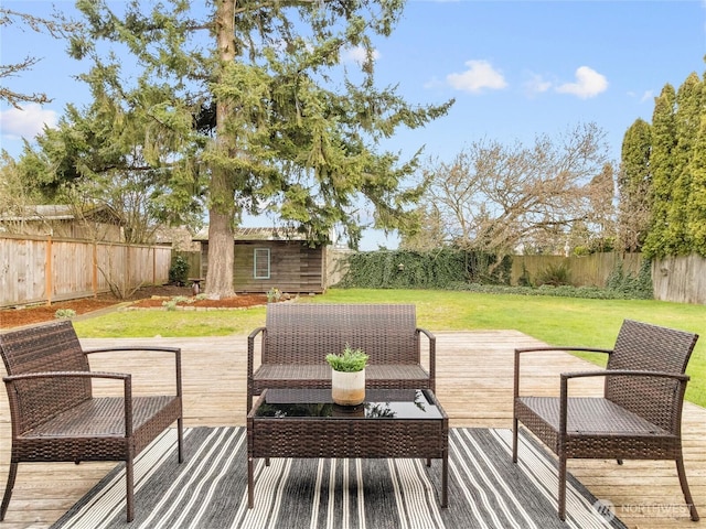 wooden terrace with a yard, an outdoor structure, a fenced backyard, and outdoor lounge area