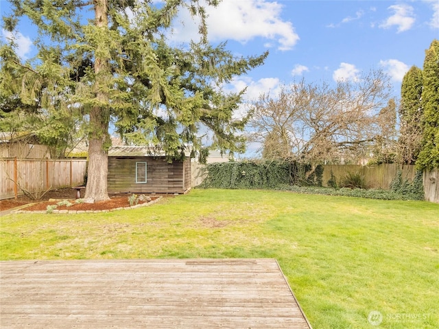 view of yard featuring a wooden deck, a fenced backyard, and an outdoor structure