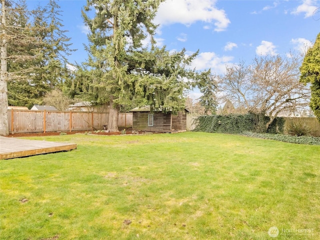 view of yard featuring a deck, an outdoor structure, a fenced backyard, and a storage shed