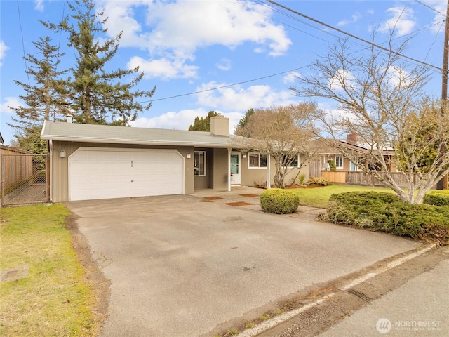 ranch-style home with a front yard, fence, driveway, an attached garage, and a chimney