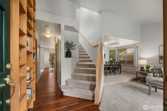 foyer entrance featuring stairs, a high ceiling, and wood finished floors