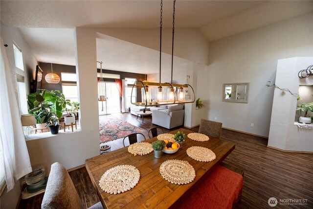 dining area with wood finished floors, baseboards, and high vaulted ceiling