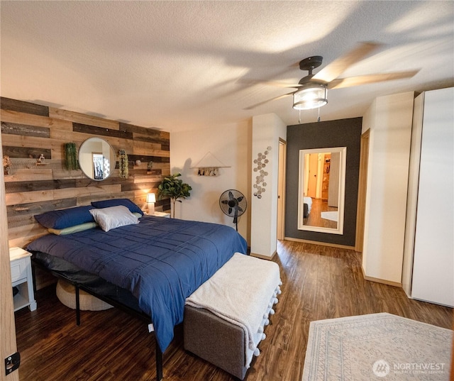 bedroom featuring baseboards, wooden walls, wood finished floors, and a textured ceiling