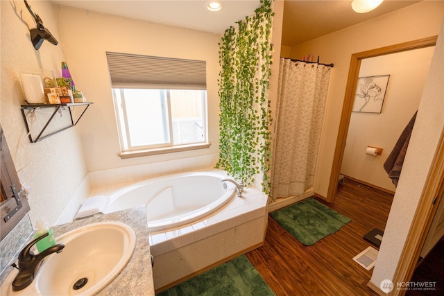 full bath with visible vents, a garden tub, a stall shower, wood finished floors, and a sink