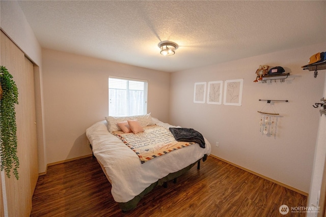 bedroom with baseboards, wood finished floors, a closet, and a textured ceiling