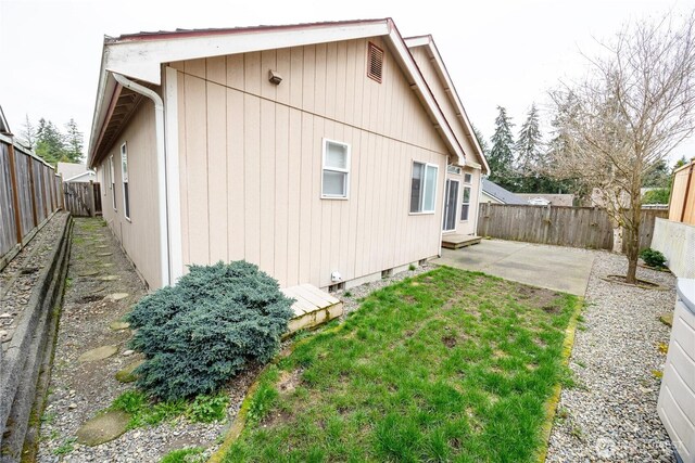 back of property with entry steps, a fenced backyard, a lawn, and a patio area