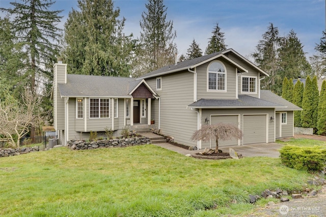 tri-level home with fence, a front yard, a chimney, a garage, and driveway